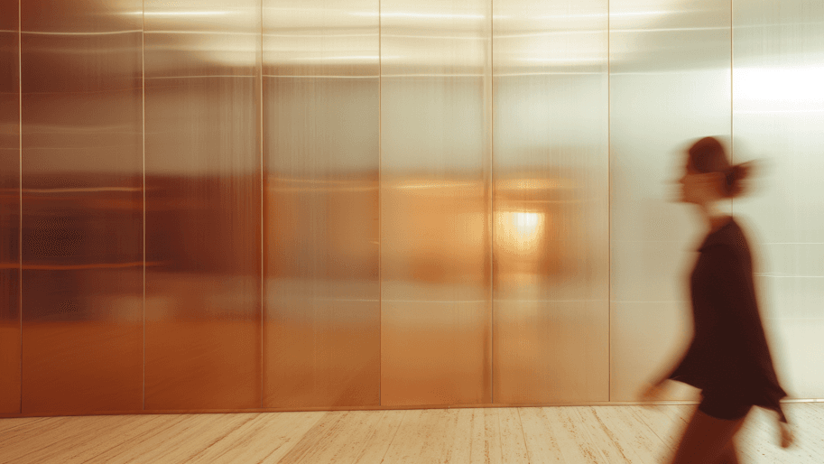 A person walking reflectively through a warm-toned corridor.